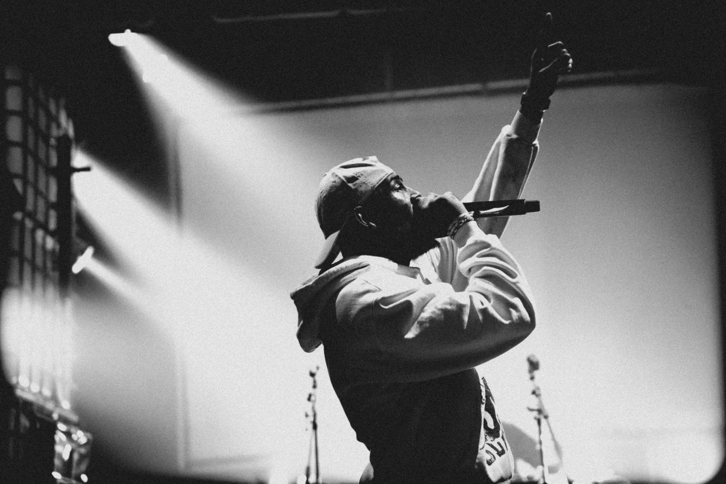 A rapper in a spotlight points up during his set at High Rollers, in black and white