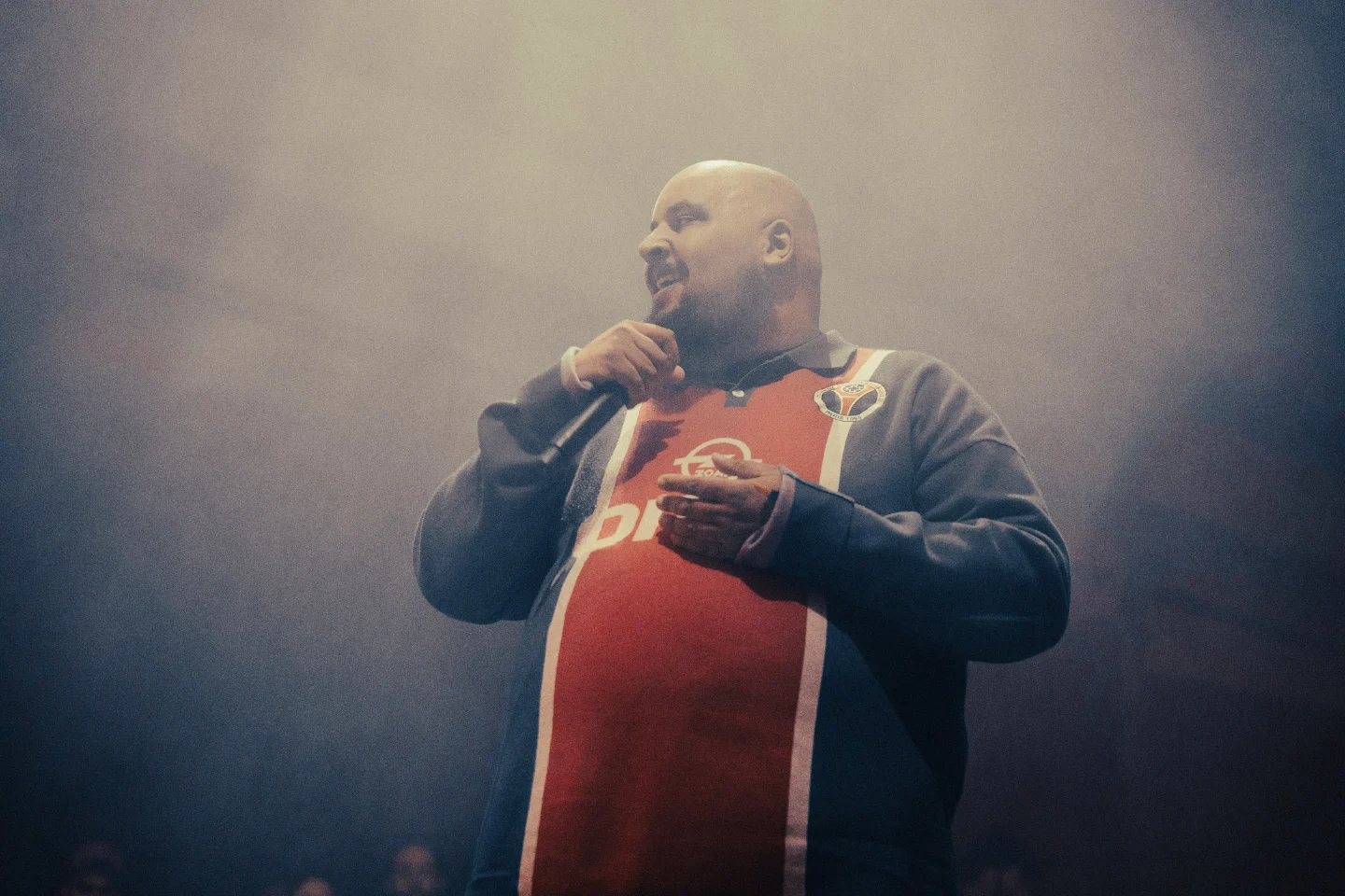 A performer with a microphone on the High Rollers stage in a haze of stage smoke