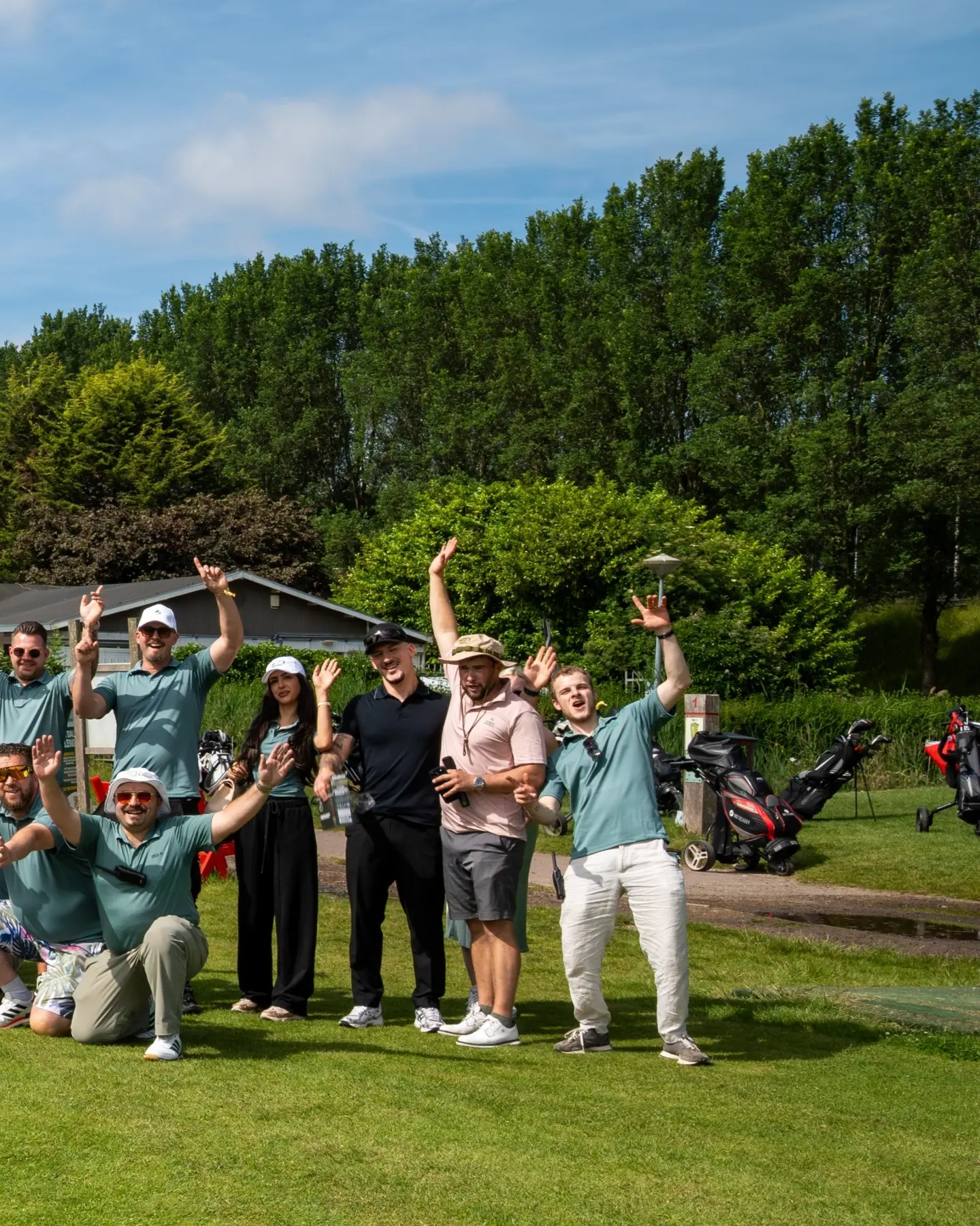 Players in matching polo shirts cheer with raised arms on the golf course at Terpy Birdies