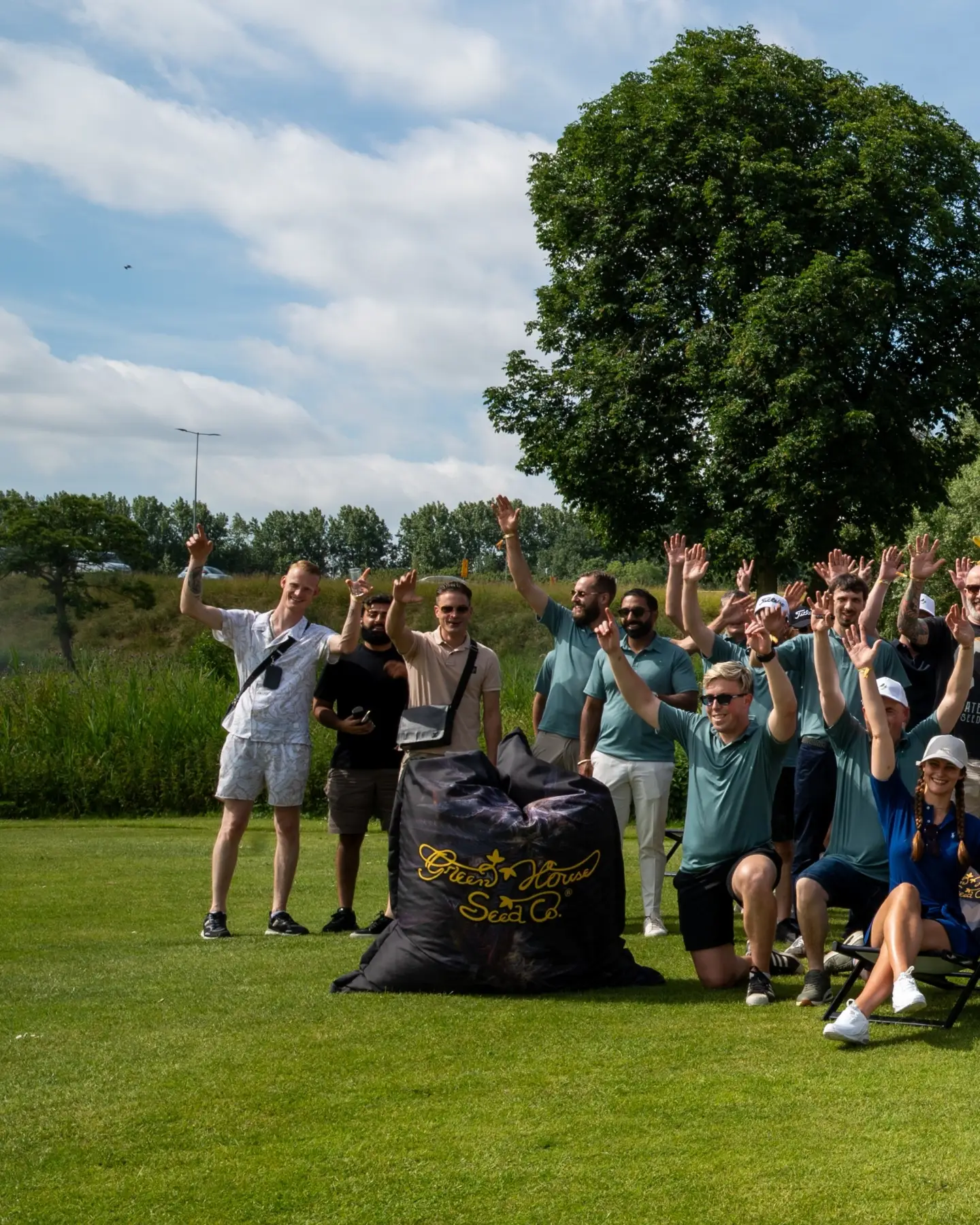 Players cheer with their arms in the air on the green at the Terpy Birdies Outdoor Tournament