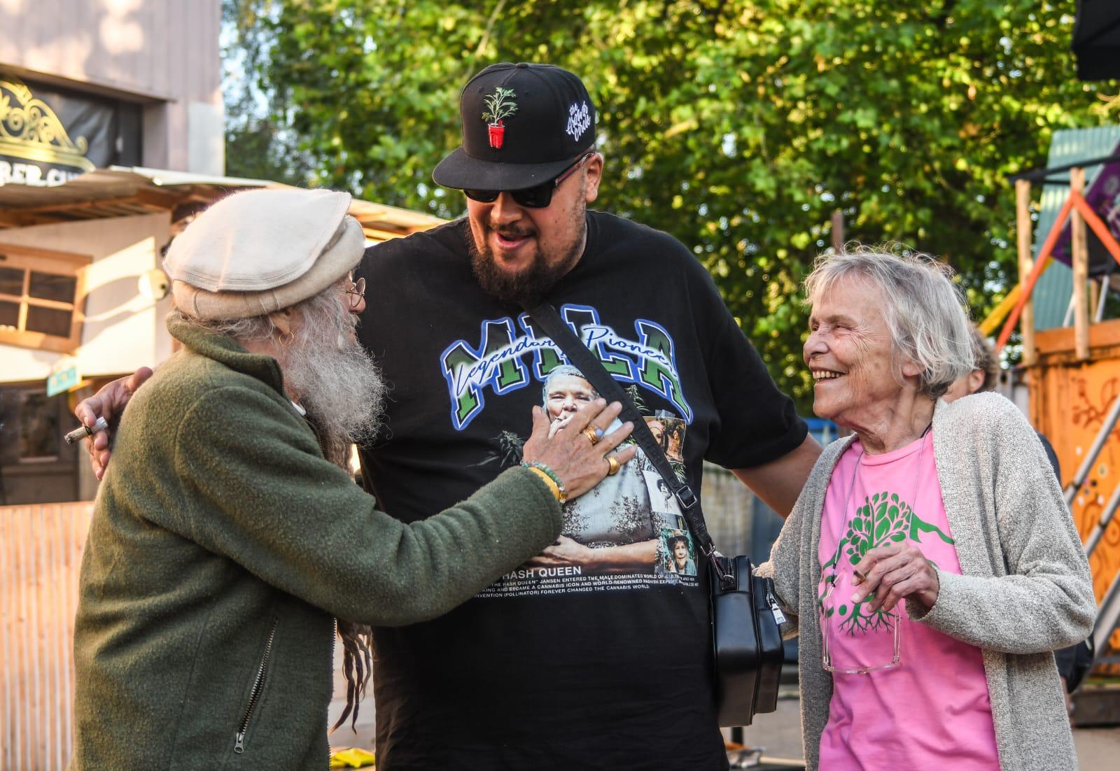 Three visitors hug and laugh together at a Never Leaf event